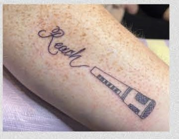 Tattoo of a microphone and the word "Reach"
