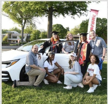 Radio station students and graduates pose with car