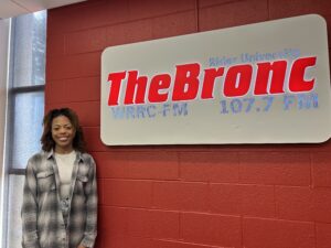Jasmine White posing with the The Bronc Sign